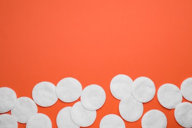 Many clean cotton pads on orange background, flat lay. Space for text