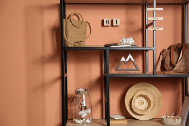 Stylish shelving unit with decorative elements near color wall. Interior design