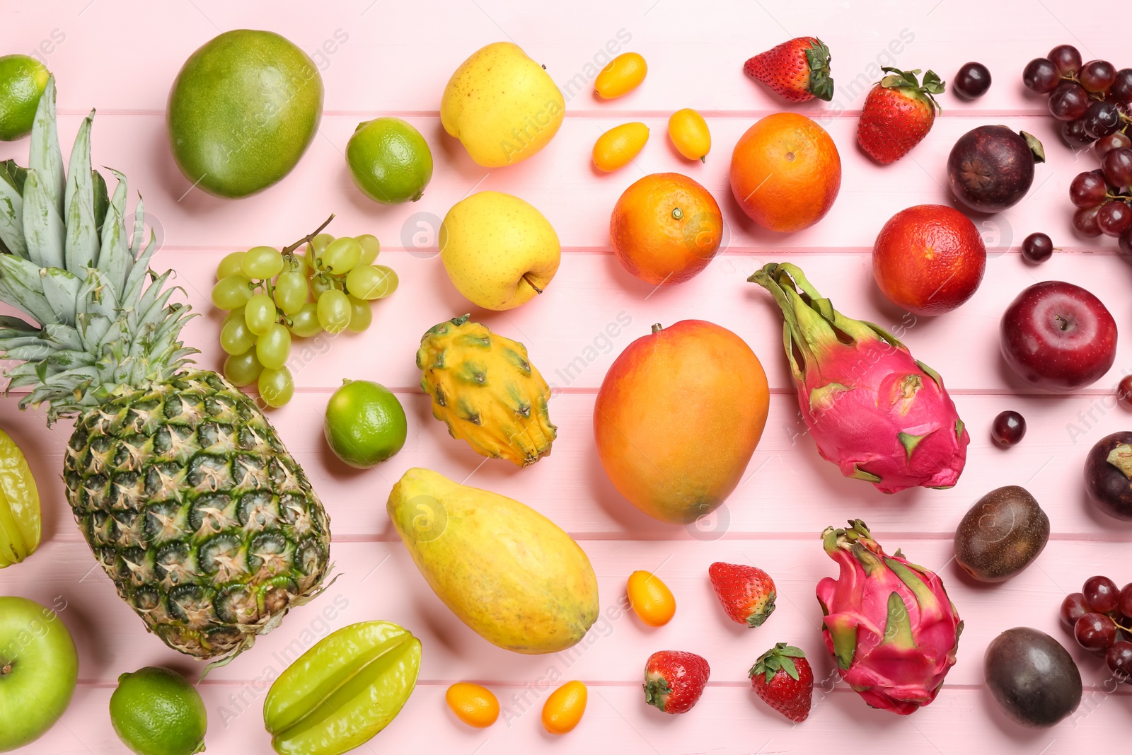 Photo of Many different delicious exotic fruits on pink wooden table, flat lay