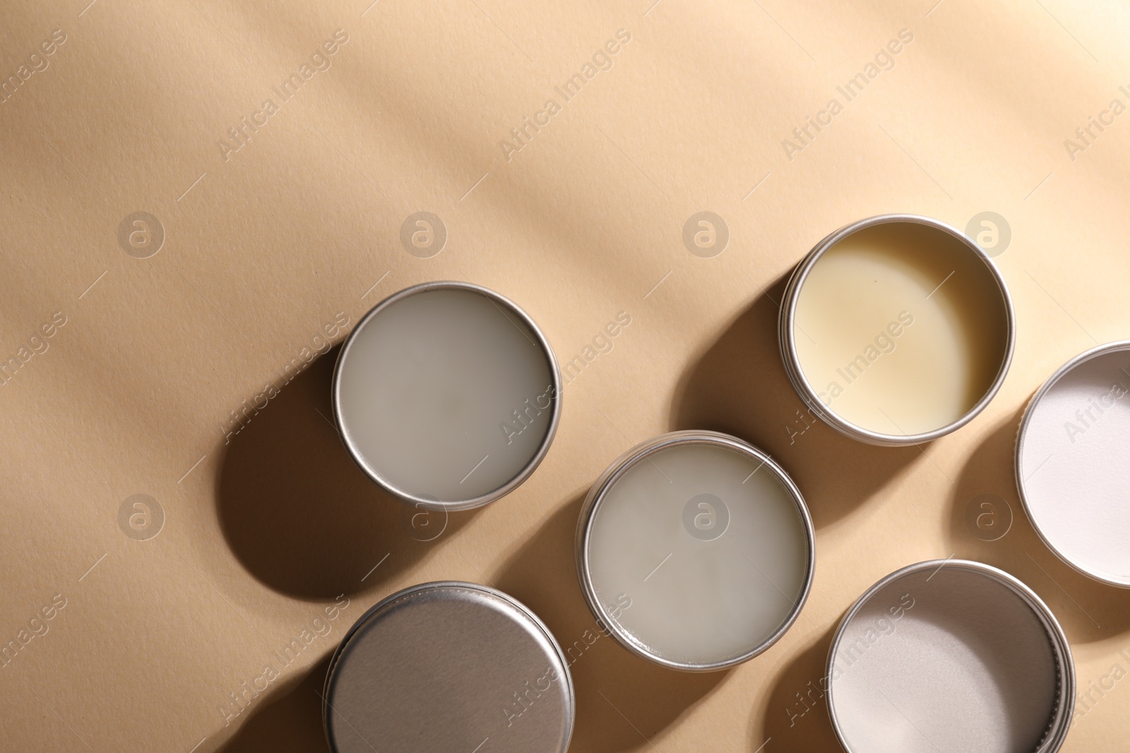 Photo of Different lip balms on beige background, flat lay