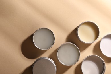 Different lip balms on beige background, flat lay