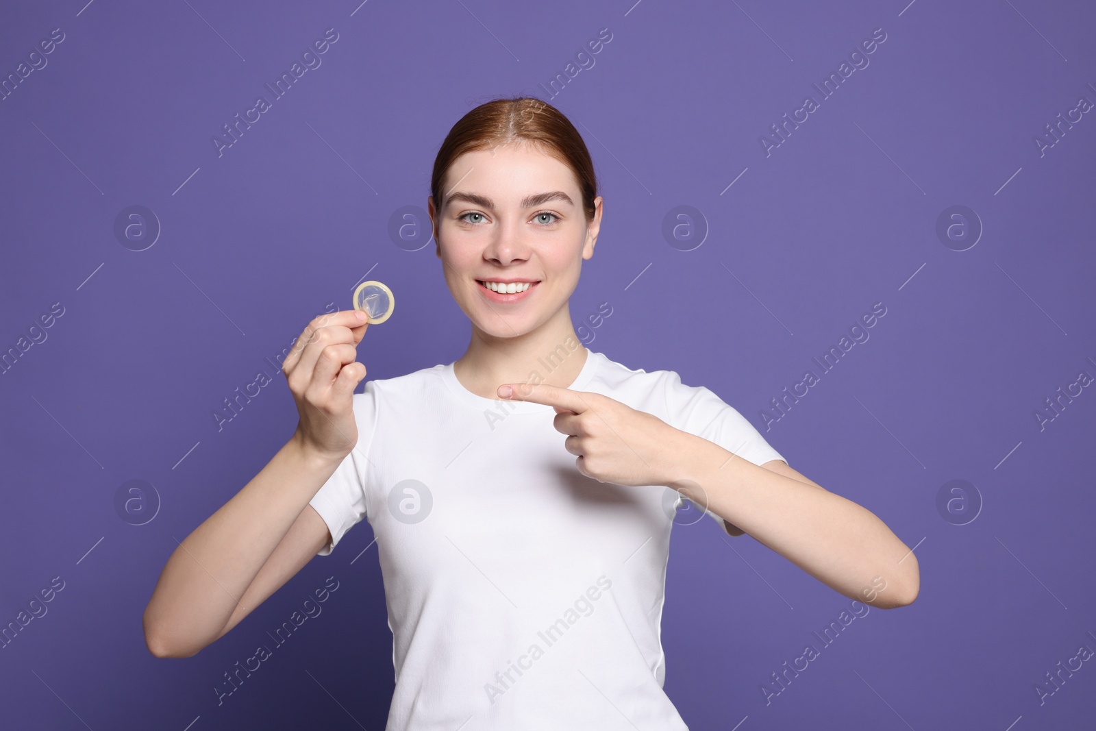 Photo of Woman holding condom on purple background. Safe sex