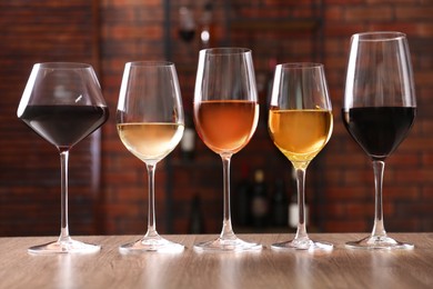 Different tasty wines in glasses on wooden table