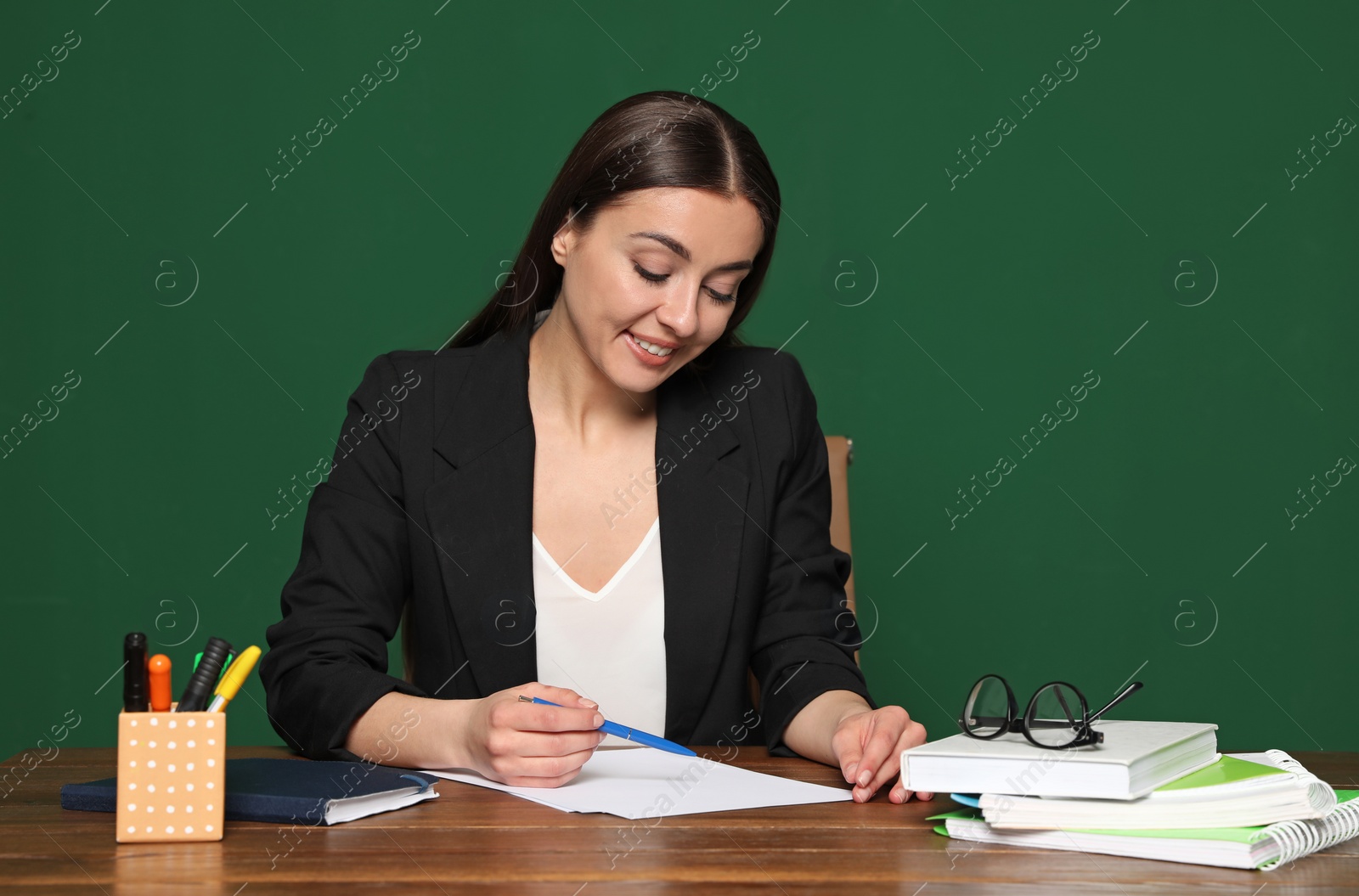 Photo of Portrait of young teacher at table against green background