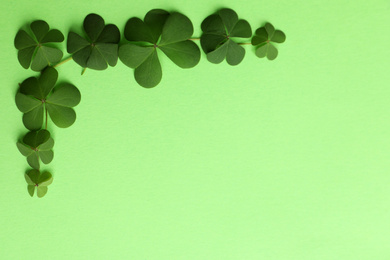 Clover leaves on green background, flat lay with space for text. St. Patrick's Day symbol