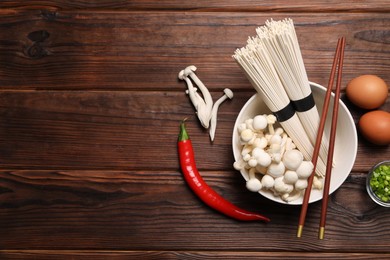 Photo of Cooking delicious ramen soup. Different ingredients and chopsticks on wooden table, flat lay. Space for text