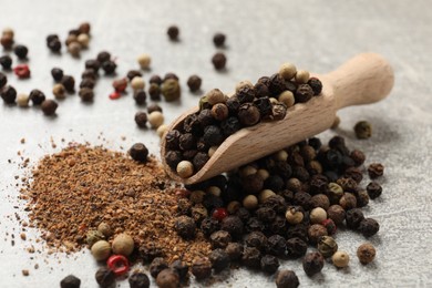 Photo of Aromatic spice. Ground and whole peppers in scoop on light grey table, closeup