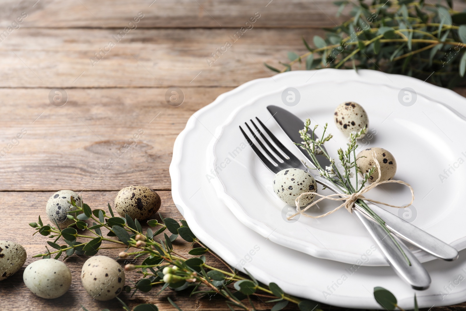 Photo of Festive Easter table setting with quail eggs and floral decor on wooden background, closeup