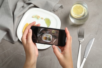 Photo of Blogger taking picture of dinner at grey table, closeup