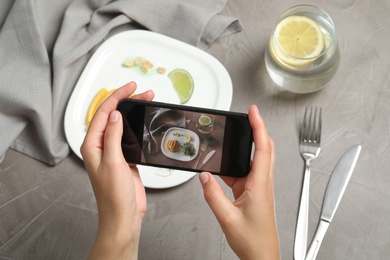 Blogger taking picture of dinner at grey table, closeup