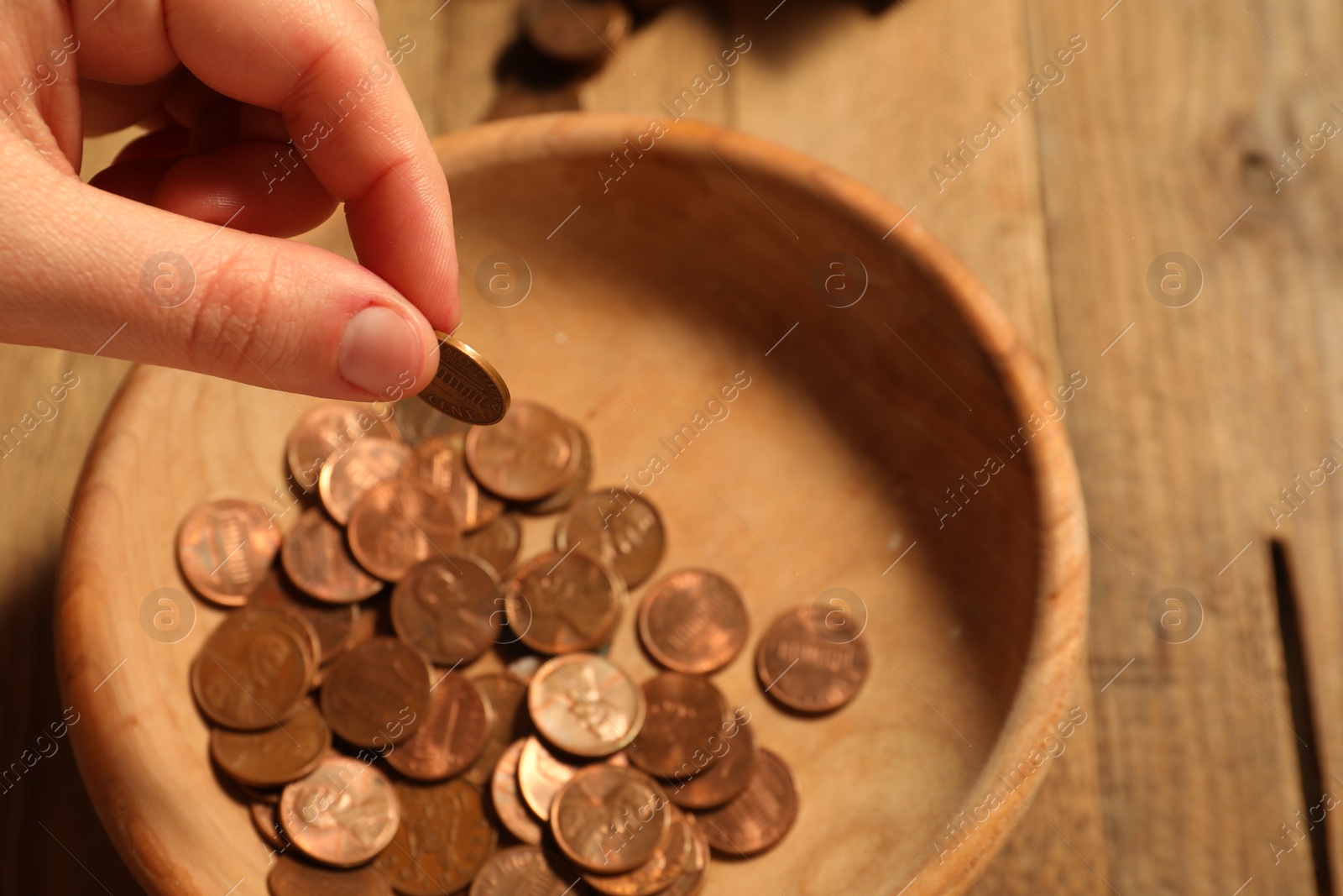 Photo of Donate and give concept. Woman putting coin into bowl at table, closeup