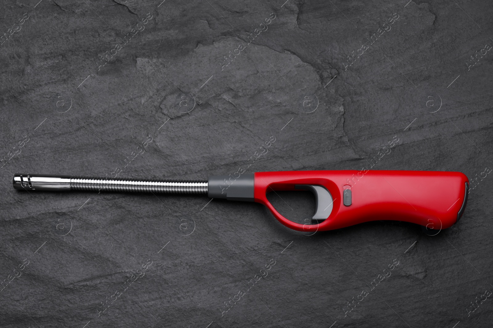 Photo of One gas lighter on black textured background, top view