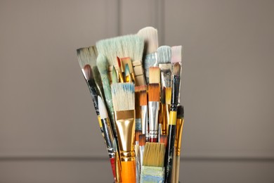 Photo of Set of different paintbrushes on grey background, closeup