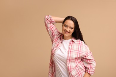 Photo of Beautiful overweight woman with charming smile on beige background. Space for text