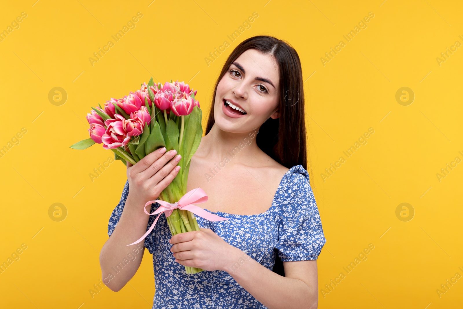 Photo of Happy young woman with beautiful bouquet on orange background