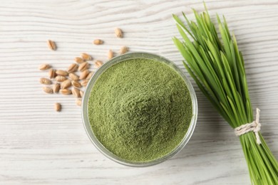 Wheat grass powder in bowl, seeds and fresh sprouts on white wooden table, flat lay