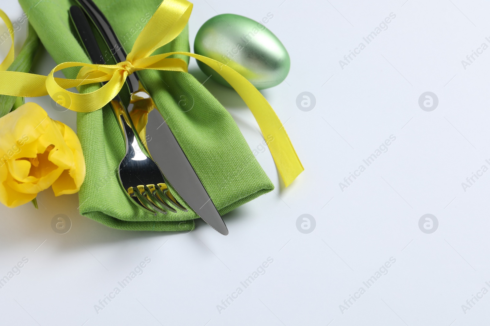 Photo of Cutlery set, Easter egg and tulip on white background, space for text. Festive table setting