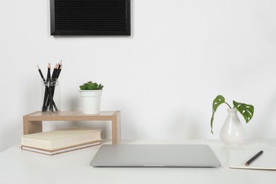 Photo of Cozy workspace with laptop and stationery on white desk at home
