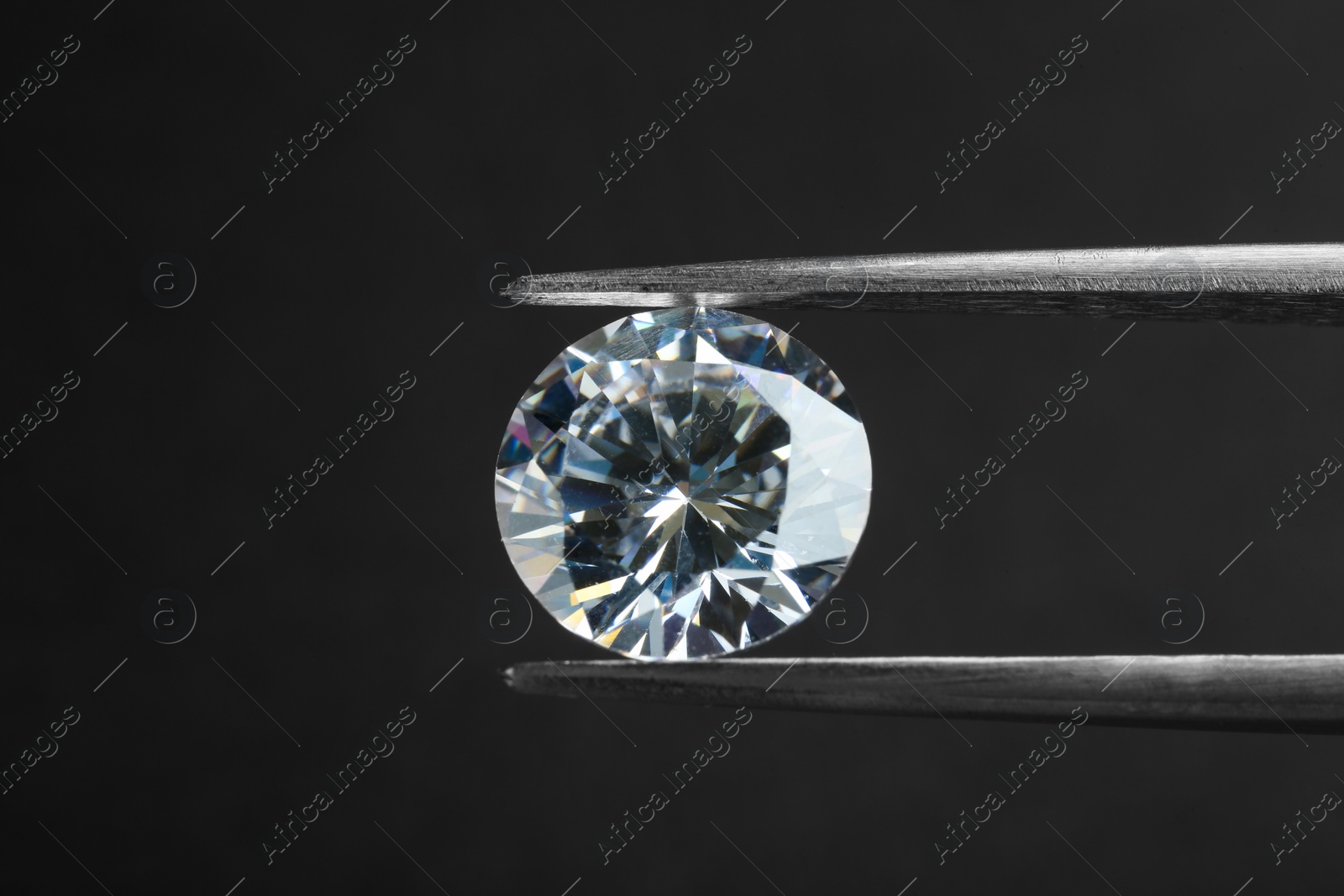 Photo of Tweezers with beautiful shiny diamond on black background, closeup