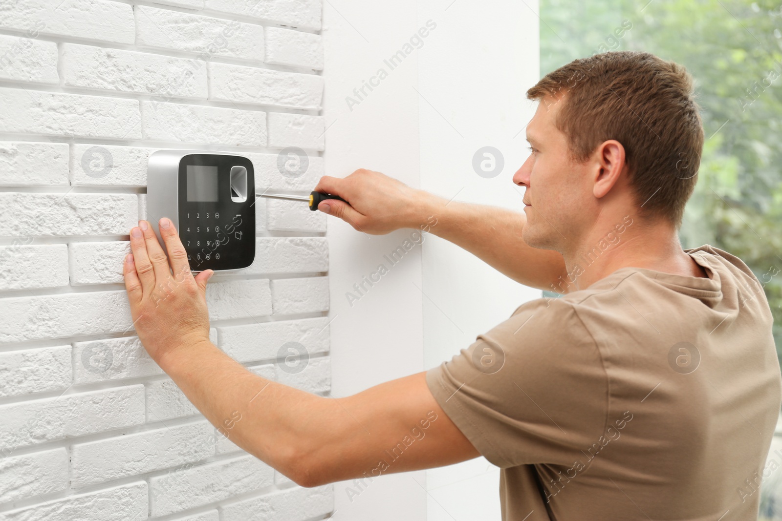 Photo of Male technician installing security alarm system indoors