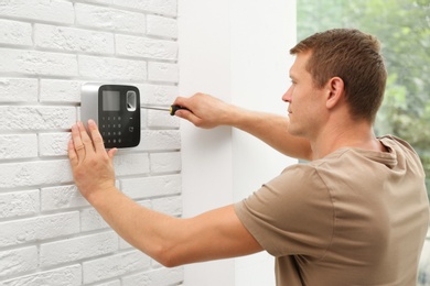 Male technician installing security alarm system indoors