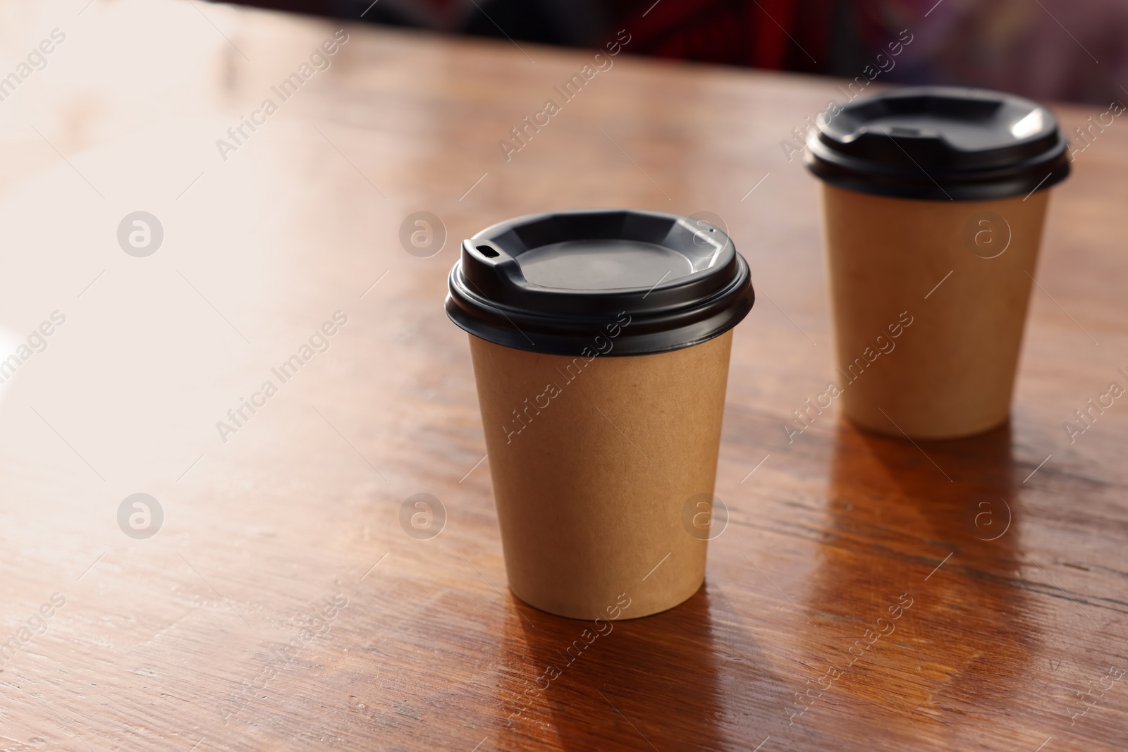 Photo of Paper coffee cups with plastic lids on wooden table