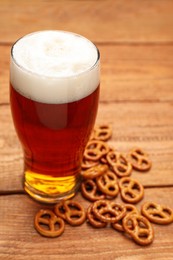 Photo of Delicious pretzel crackers and glass of beer on wooden table