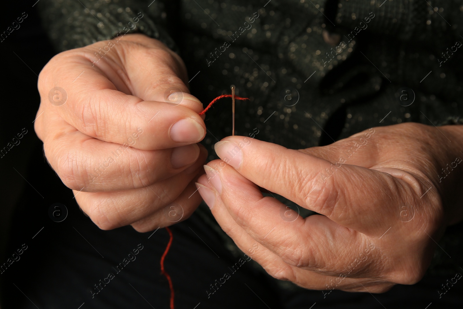 Photo of Closeup view of woman threading needle. Sewing equipment