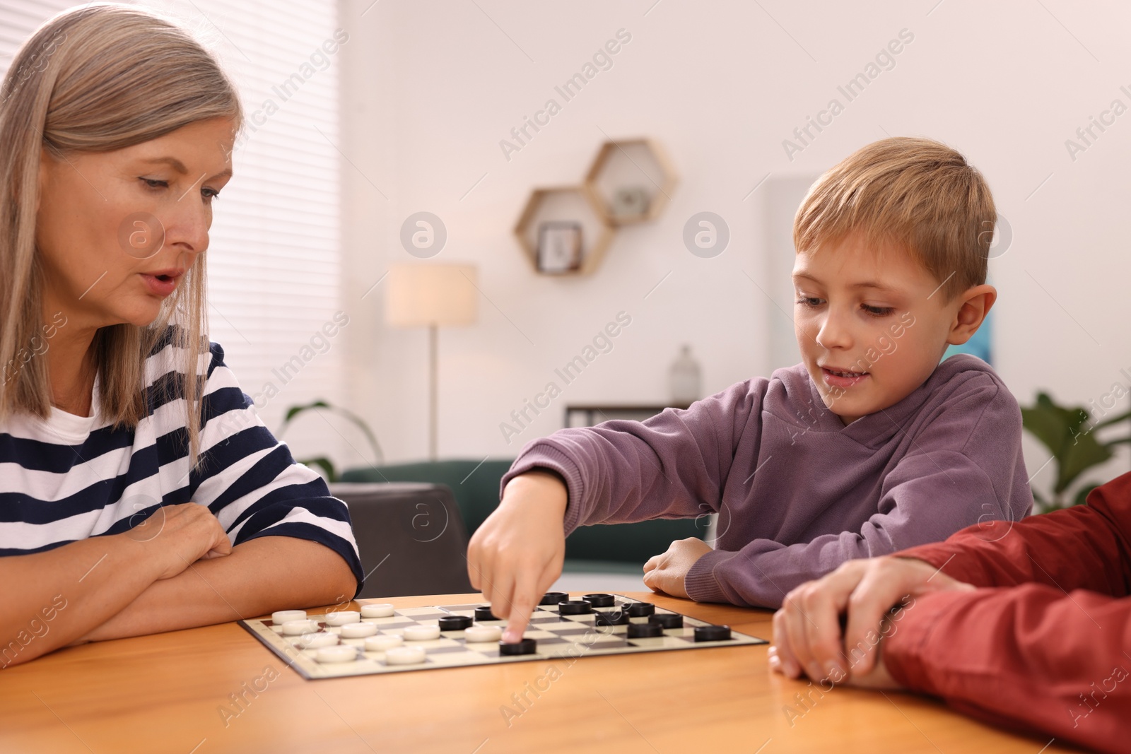 Photo of Family playing checkers at wooden table in room