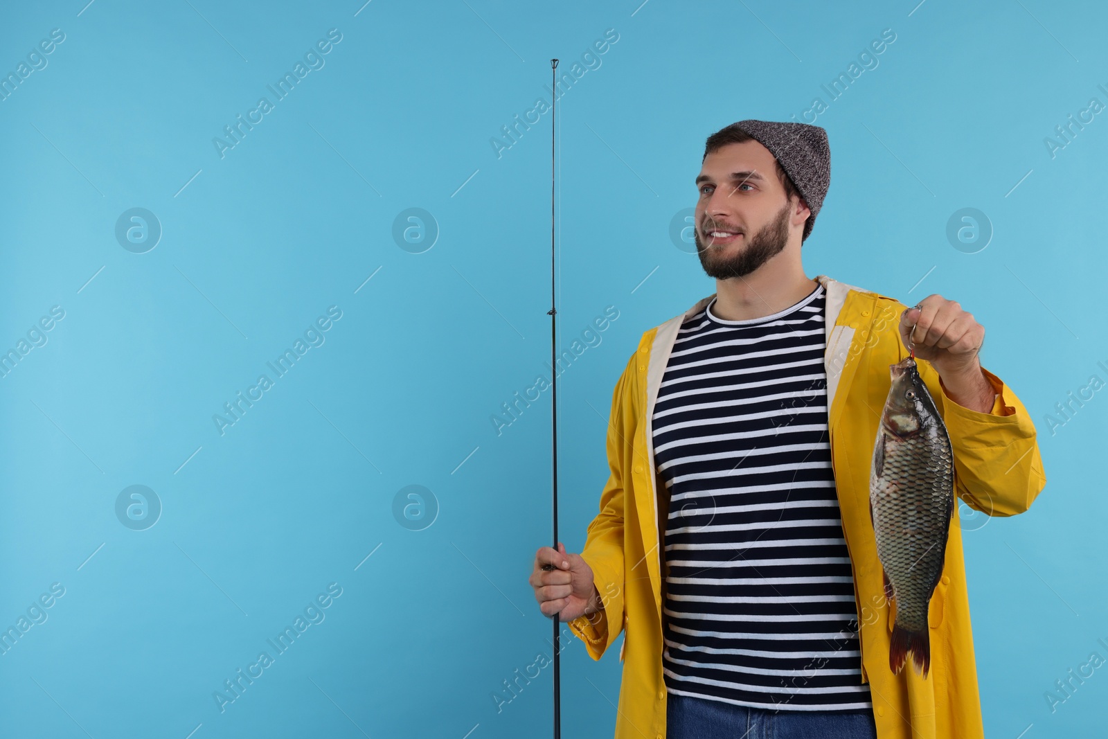 Photo of Fisherman with rod and catch on light blue background, space for text