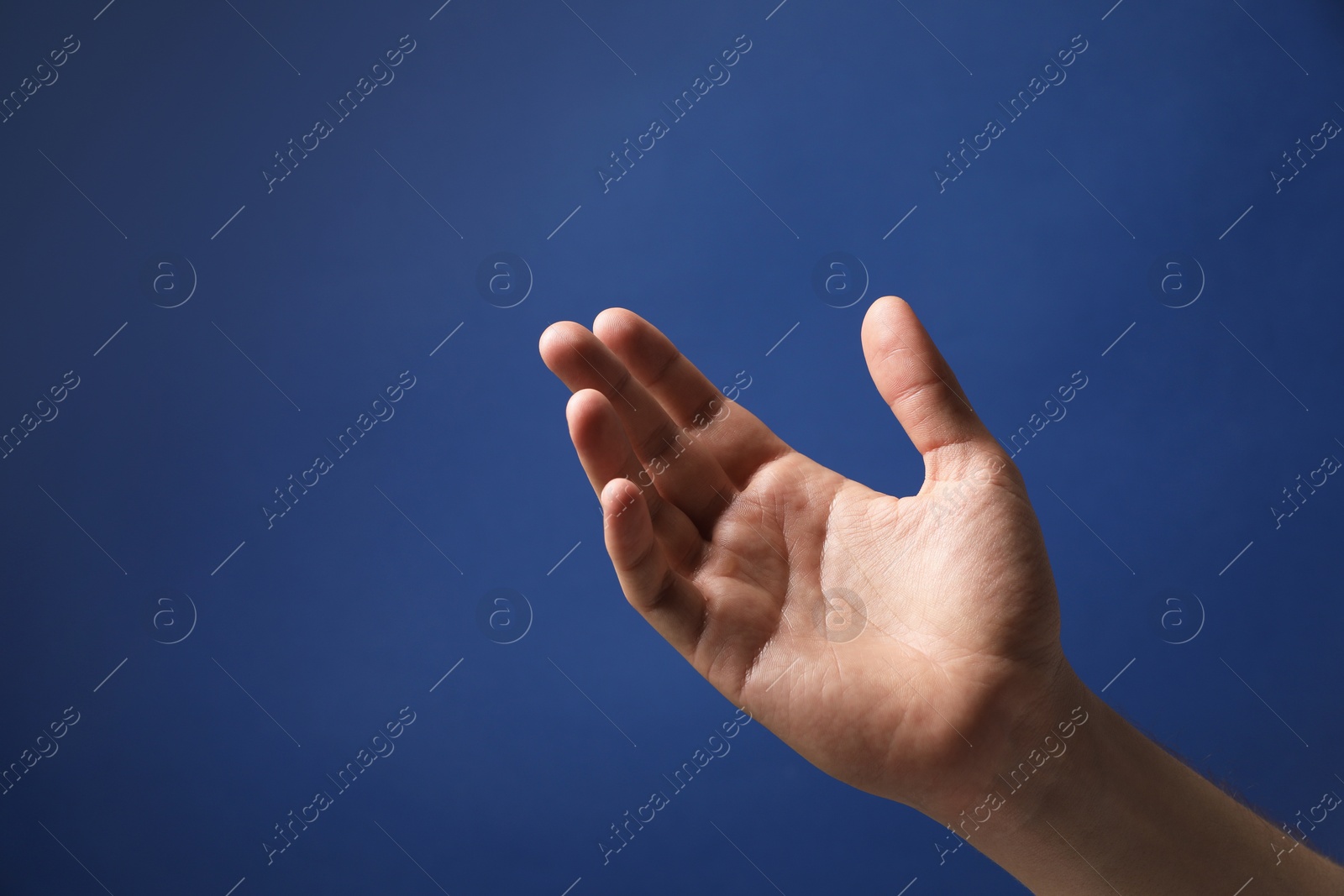 Photo of Man holding something in hand on blue background, closeup