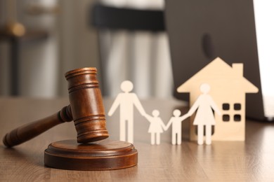 Law concept. Gavel, figures of parents with children and house on wooden table, closeup