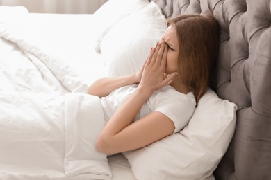 Photo of Young woman with terrible headache lying in bed