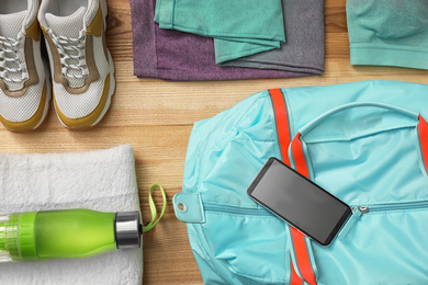 Flat lay composition with sports bag on wooden background