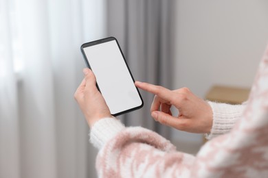 Woman using mobile phone indoors, closeup view