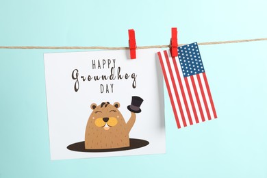 Photo of Happy Groundhog Day greeting card and American flag hanging on turquoise background