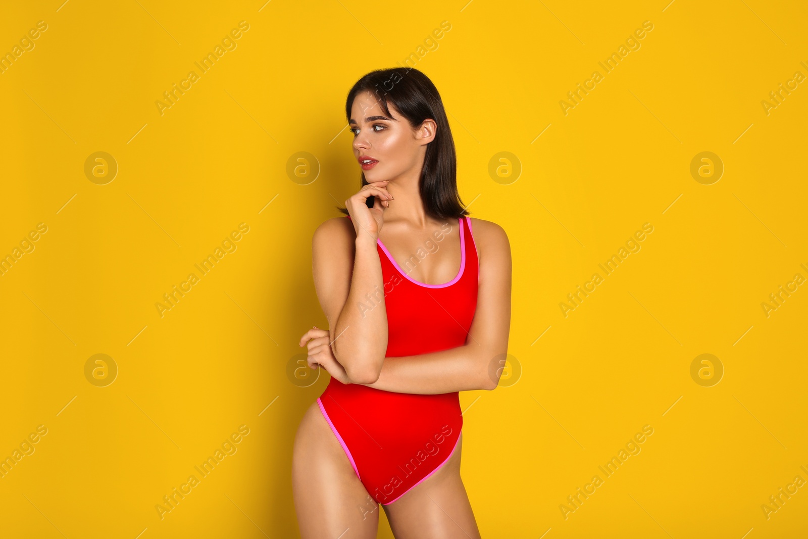 Photo of Beautiful woman in red swimsuit on yellow background