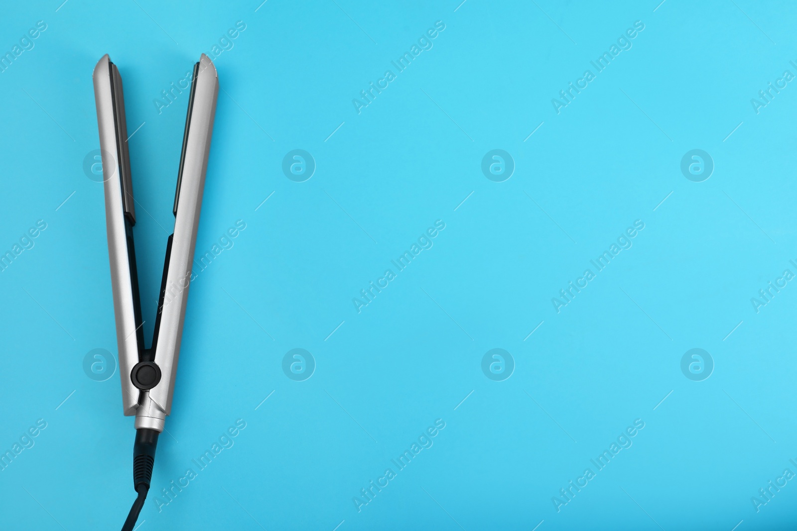 Photo of Modern hair iron for straightening on color background, top view with space for text