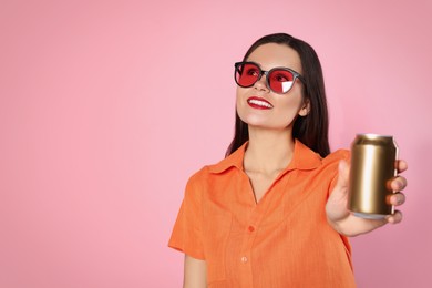 Photo of Beautiful young woman in stylish sunglasses holding tin can with beverage on pink background. Space for text
