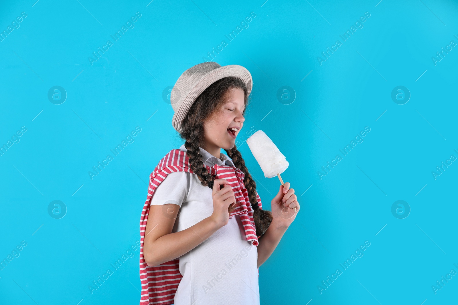 Photo of Little girl with cotton candy on color background