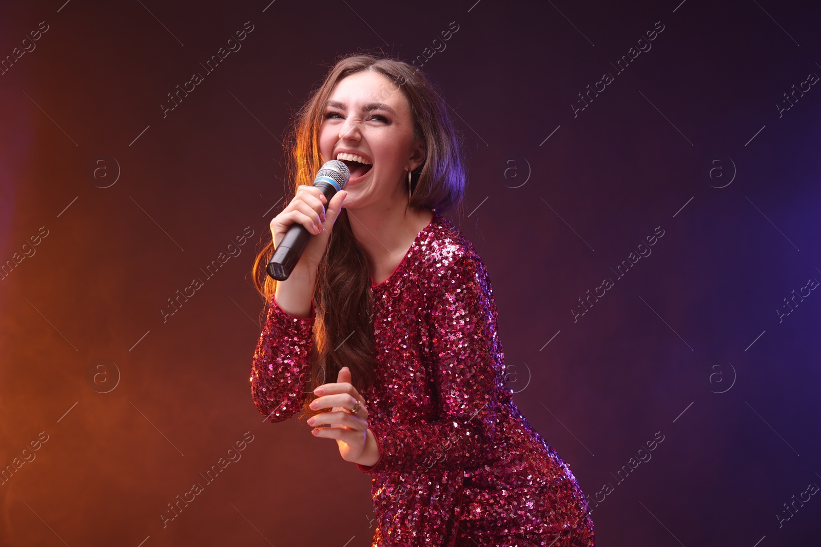 Photo of Emotional woman with microphone singing in color lights