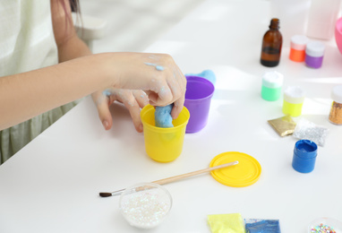 Little girl making DIY slime toy at table, closeup