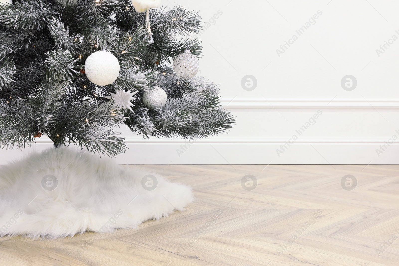 Photo of Beautiful decorated Christmas tree with skirt in room, closeup. Space for text