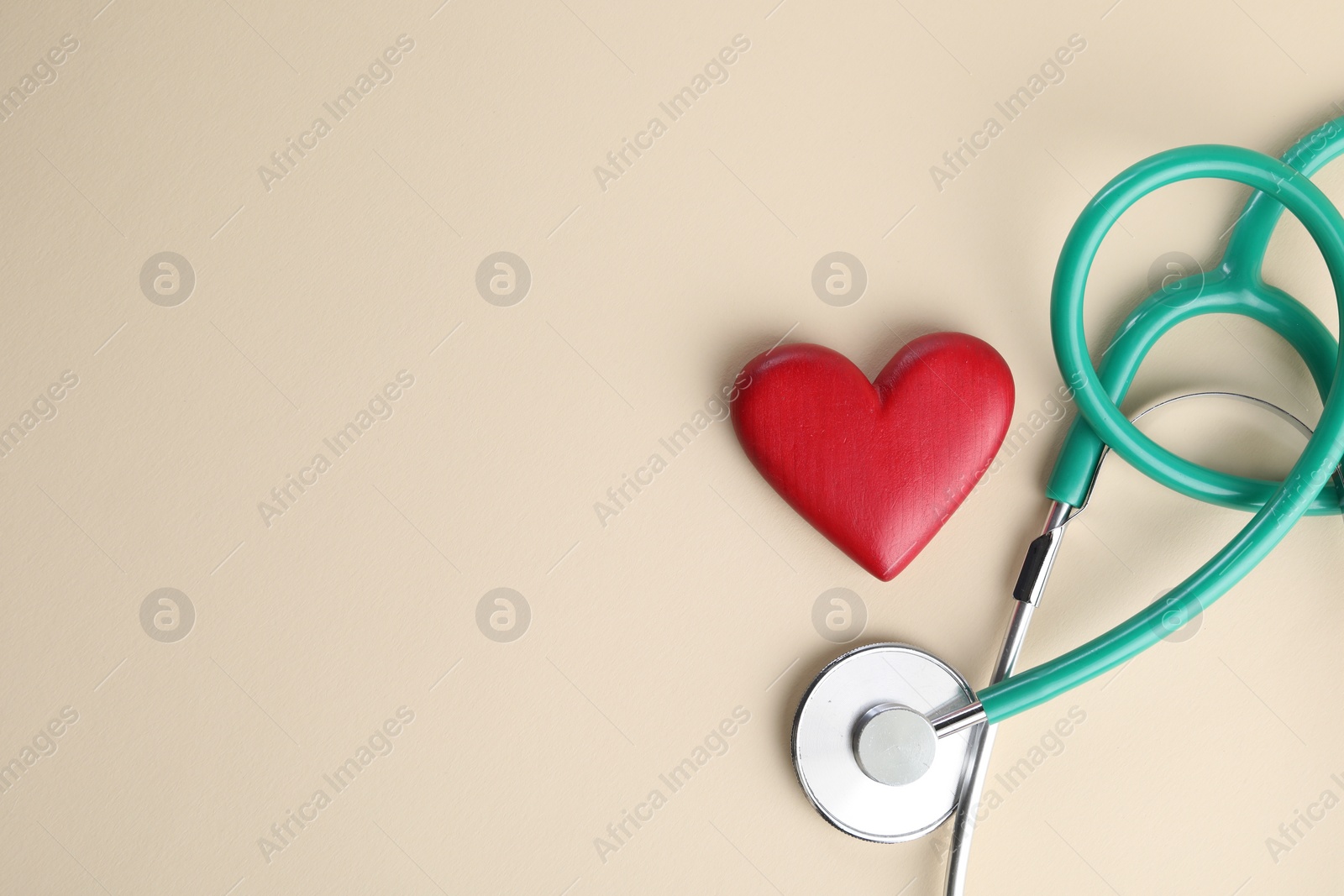 Photo of Stethoscope and red heart on beige background, top view. Space for text