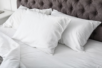 Photo of Soft white pillows on comfortable bed, closeup