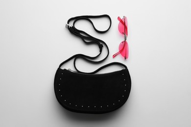 Photo of Stylish woman's bag and sunglasses on light background, flat lay