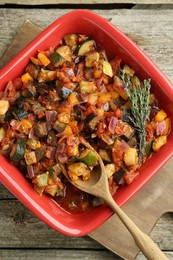 Photo of Dish with tasty ratatouille on wooden table, top view
