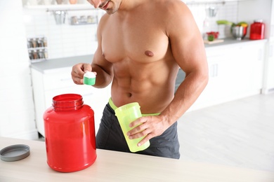 Young shirtless athletic man preparing protein shake in kitchen, closeup view