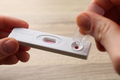Photo of Woman dropping buffer solution onto disposable express test cassette at table, closeup