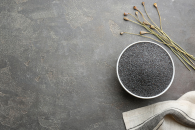 Photo of Dried poppyheads and bowl with seeds on grey table, flat lay. Space for text